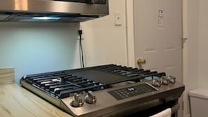 A kitchen with a stainless steel stove, a microwave above it, and a white door in the background. - tiny house backyard cabin getaway in Detroit (Detroit)