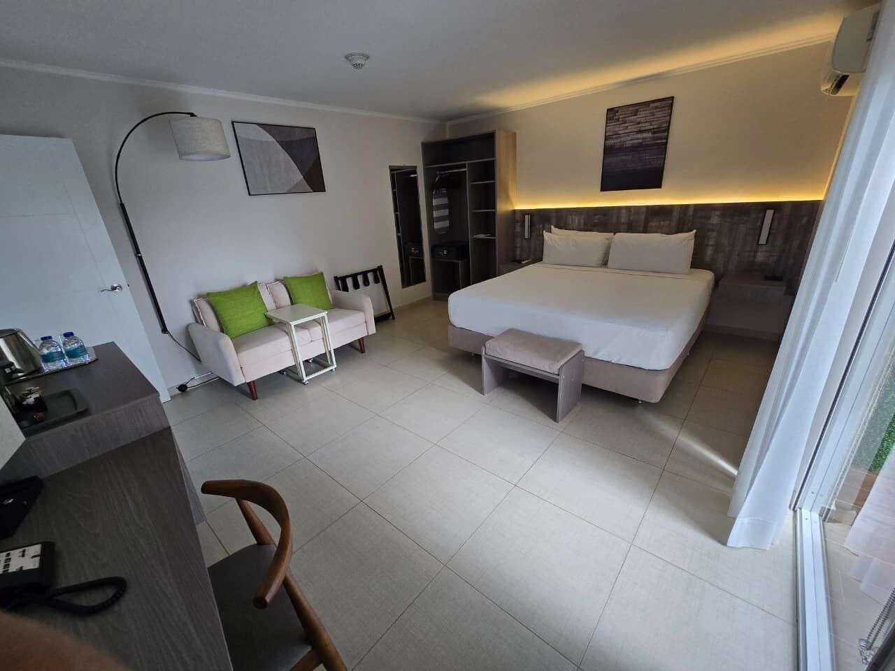 A hotel room with a bed, a desk, a chair, a sofa, and a wardrobe.
