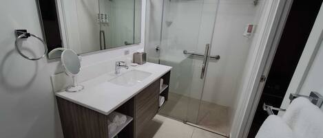 A modern bathroom with a glass-enclosed shower, a white sink with a mirror, and a toilet.