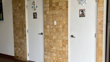 A hallway with two white doors, a tiled wall, and a wooden floor.