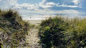 A beach path leading to the ocean with a person walking. - Luxurious & Cozy Oceanfront Escape Steps from the Sand with Sweeping Ocean Views (Rockaway Beach)