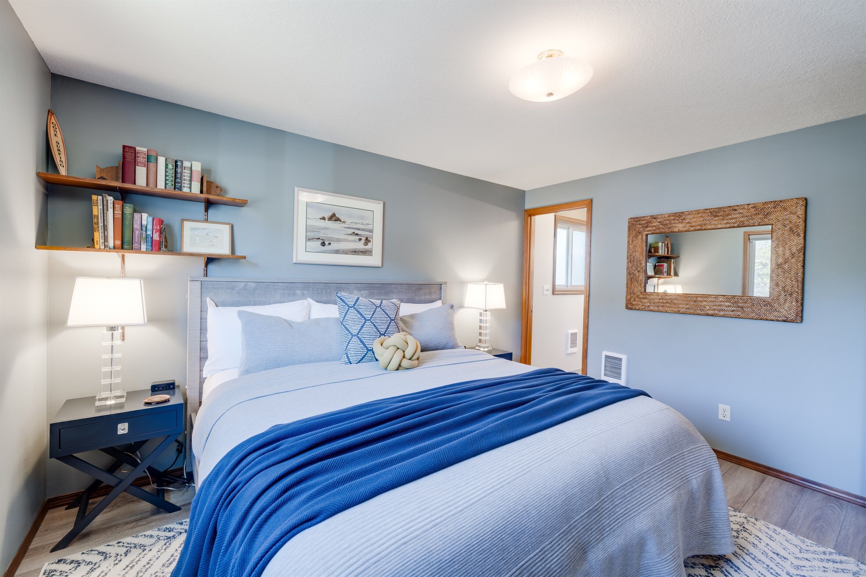Une chambre à coucher bien rangée, avec un lit, des tables de chevet, une bibliothèque et un miroir.