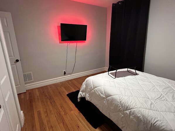 A bedroom with a bed, a flat-screen TV mounted on the wall, and a door. - Picture A City View (St. Louis)
