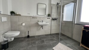A modern bathroom with a toilet, sink, and glass shower enclosure.