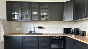 A modern kitchen with dark cabinetry, a stainless steel sink, a built-in oven, and a microwave.