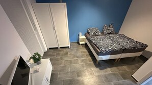 A bedroom with a bed, a TV, a desk, and a wardrobe.