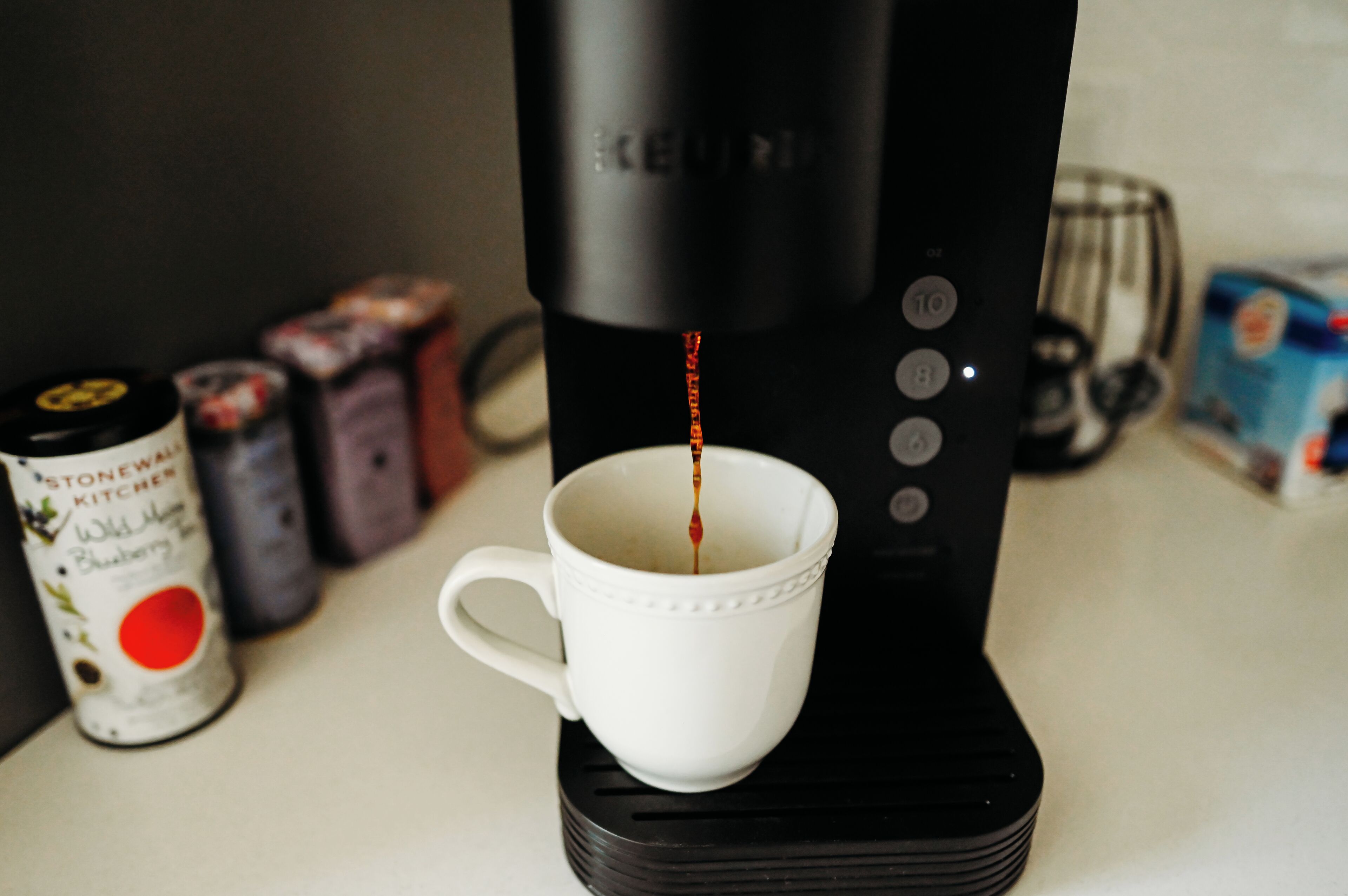 A coffee maker dispensing coffee into a white cup.