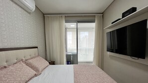 Et hotelværelse med en seng, et fjernsyn ophængt på væggen og udsigt over byen gennem vinduet.