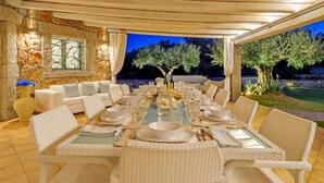 Un área de comedor al aire libre con un muro de piedra, un sofá y una mesa dispuesta para una comida.