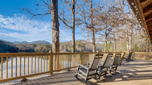 Une terrasse en bois avec des bancs, donnant sur un lac et des montagnes.