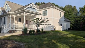 Ein zweistöckiges Haus mit Veranda, Garage und einem gepflegten Rasen.