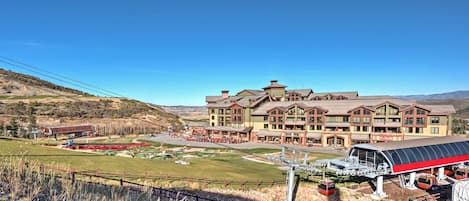 Un hotel grande con varias construcciones, un telesilla y montañas al fondo.