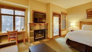 Een hotelkamer met een open haard, een bed, een bureau en een stoel.