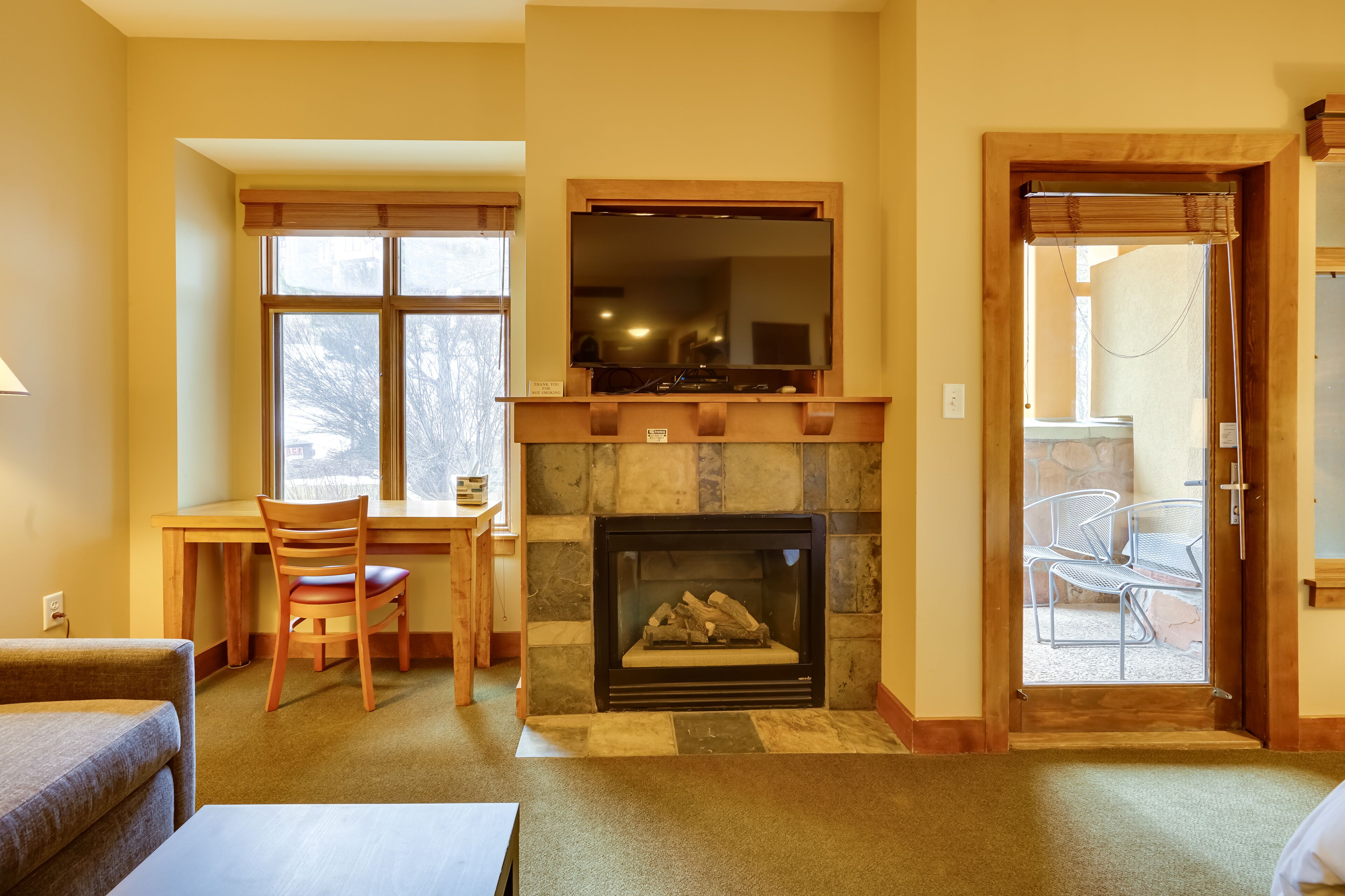Una sala de estar con chimenea, un comedor con mesa y sillas, y vista a través de un ventanal.