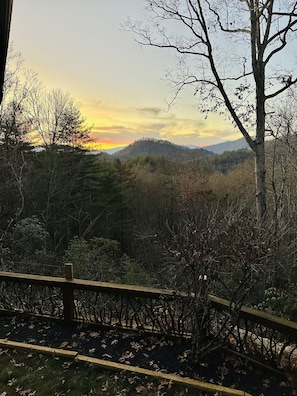Eine bewaldete Landschaft mit einem Holzzaun und Blick auf ferne Hügel.
