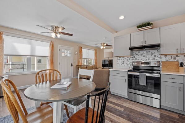 A modern kitchen with white cabinets, a large oven, and a dining area with a round table and chairs.
