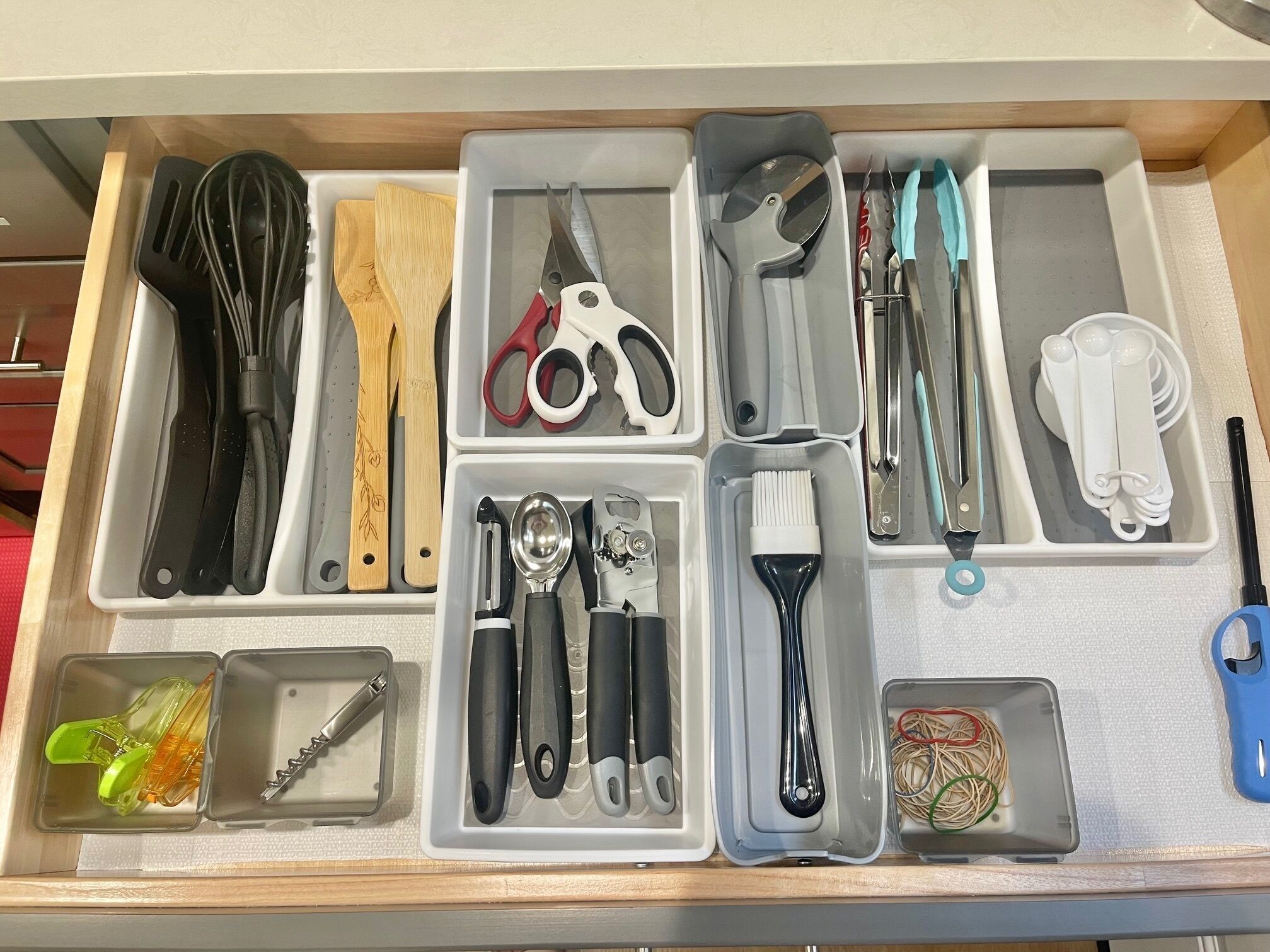 Eine Schublade mit verschiedenen Küchenutensilien und Werkzeugen, ordentlich in Fächern angeordnet.