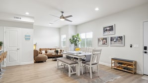 A spacious living area with a dining table, chairs, a bench, a ceiling fan, and a shoe rack. - Disney Luxury 3 Bedroom - Comfortable 12 Guests + EV (Midway City)