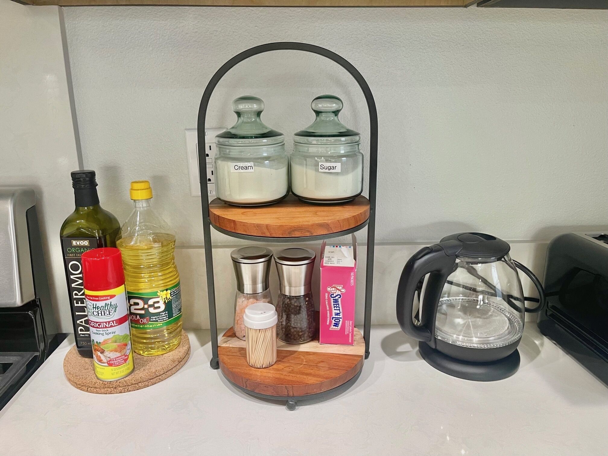 A kitchen counter with a wooden spice rack holding jars labeled 'Cream' and 'Sugar'.