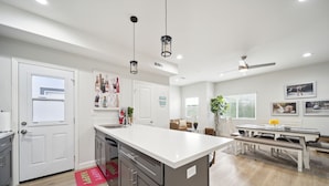 A modern kitchen with a central island, white cabinetry, and pendant lighting. - Disney Luxury 3 Bedroom - Comfortable 12 Guests + EV (Midway City)