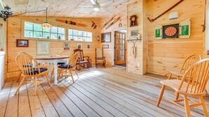 A wooden cabin interior with a dining table, chairs, a ceiling fan, and a dartboard. - Duplex Unit, 2 Mi to Chittenden Reservoir! (Chittenden)