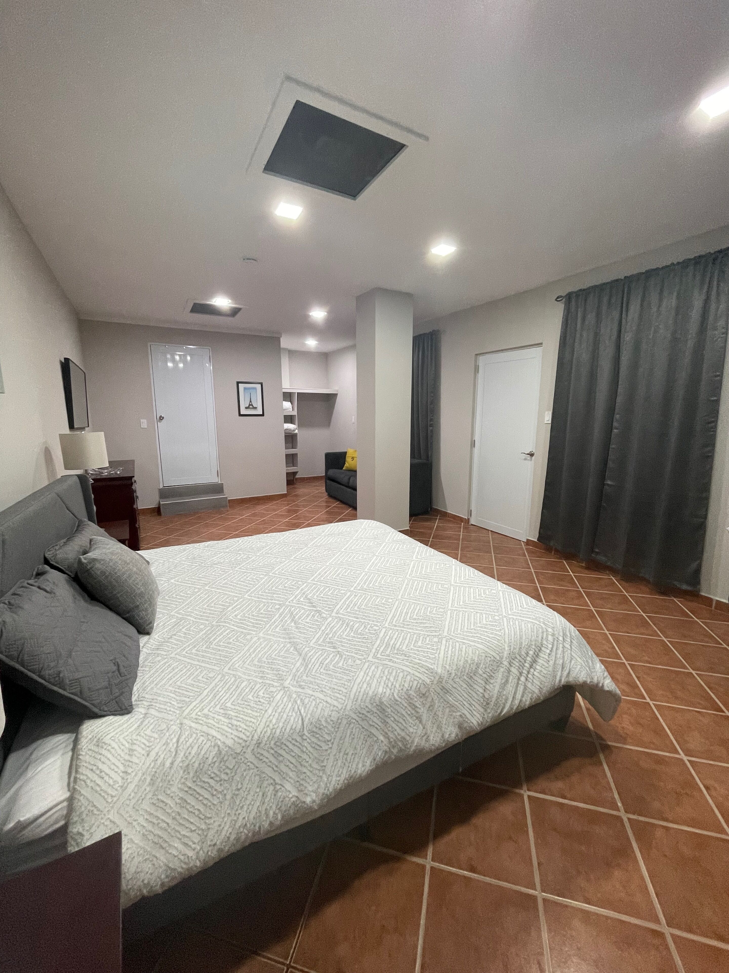 Un dormitorio con una cama, una mesita de noche, una lámpara y una puerta.