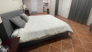 A hotel room with a large bed, a desk with a lamp, a chair, a wardrobe, and a bathroom visible in the background. - Shorebreak Hotel (Aguadilla)