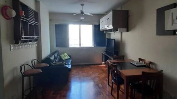 Un salon comprenant un canapé, une table à manger et des chaises. On y trouve également un téléviseur et un ventilateur de plafond.