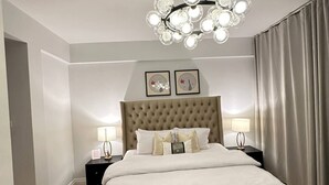 Un dormitorio con una cama grande, dos mesitas de noche, una araña y vistas al exterior.