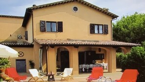 Ein zweistöckiges Haus mit Swimmingpool, Sitzgelegenheit im Freien und einer überdachten Terrasse.