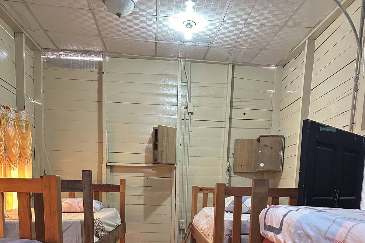 A cabin interior with bunk beds, a wooden door, and a ceiling light fixture.