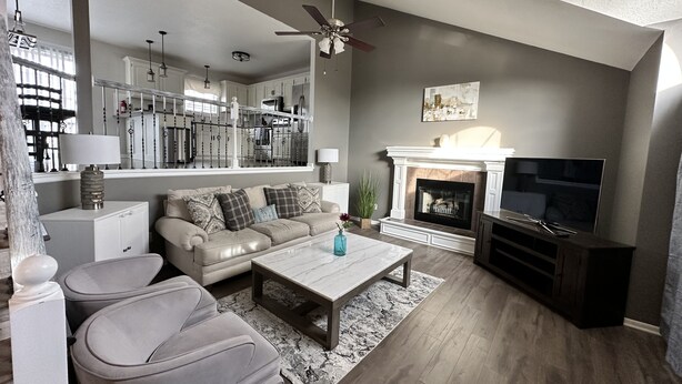 A modern living room with a sofa, coffee table, TV, fireplace, and kitchen in the background.