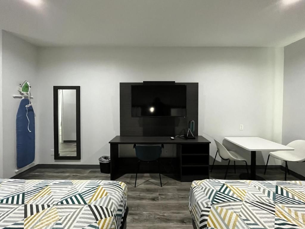 A hotel room with a bed, a desk, a chair, a TV, and a mirror.