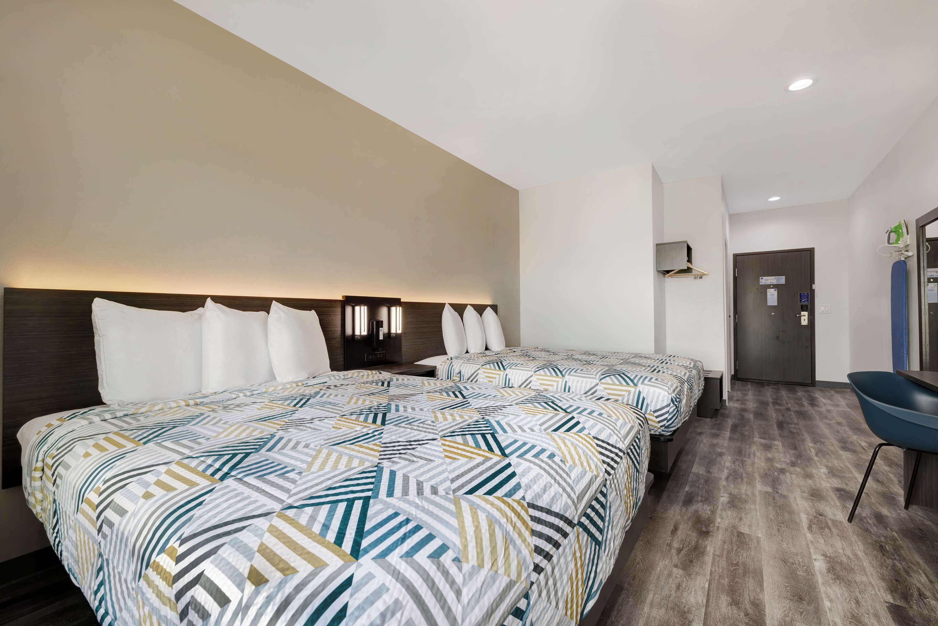 Ein Hotelzimmer mit zwei Betten, einem Schreibtisch und einem Stuhl.
