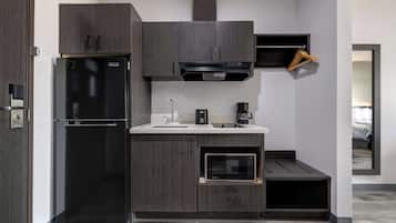 A compact kitchen with a built-in refrigerator, microwave, and coffee maker.