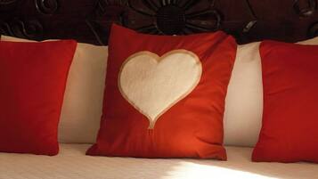 A bed with red and white pillows, a wooden headboard, and a striped rug.