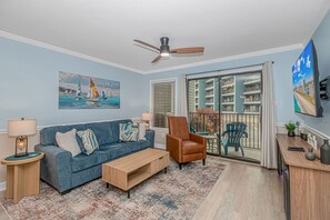 Ein Wohnzimmer mit Sofa, Sessel, Couchtisch und Deckenventilator.