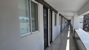 A corridor with a tiled floor, a series of doors, and windows along one side. - La Vid Aguascalientes (Aguascalientes)