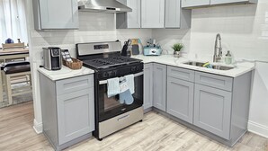 A modern kitchen with grey cabinets, a stainless steel range hood, a built-in oven, and a sink with a faucet. - Charming, luxe, modern home near Naval base, Six flags, Casino, Gurnee Mills (Waukegan)