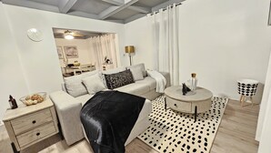 A modern bedroom with a bed, bedside tables, a round side table, a small stool, and a patterned rug. - Charming, luxe, modern home near Naval base, Six flags, Casino, Gurnee Mills (Waukegan)