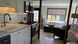Una cocina moderna con gabinetes blancos, una estufa de acero inoxidable y un amplio ventanal.