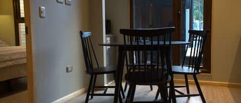A room with a bed, a table with chairs, a small heater, and a window with a view.