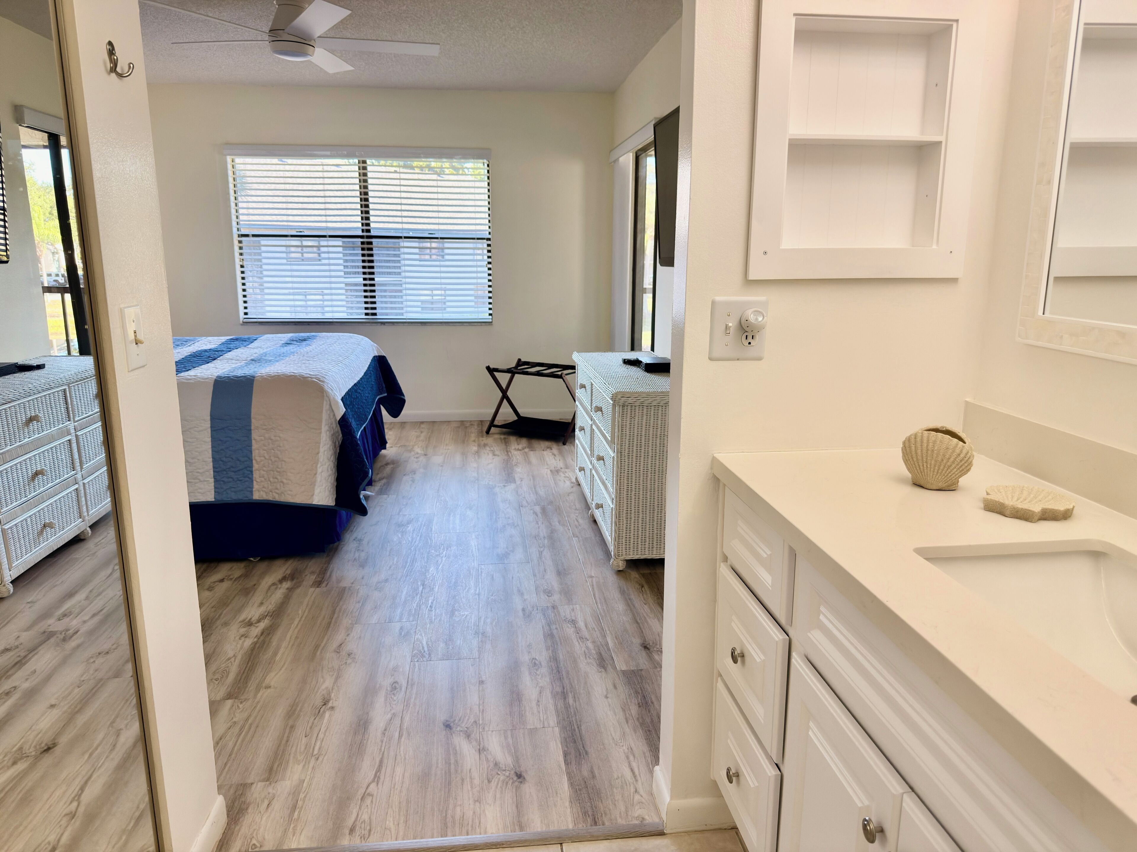 A bedroom with a bed, dresser, and a window with blinds.