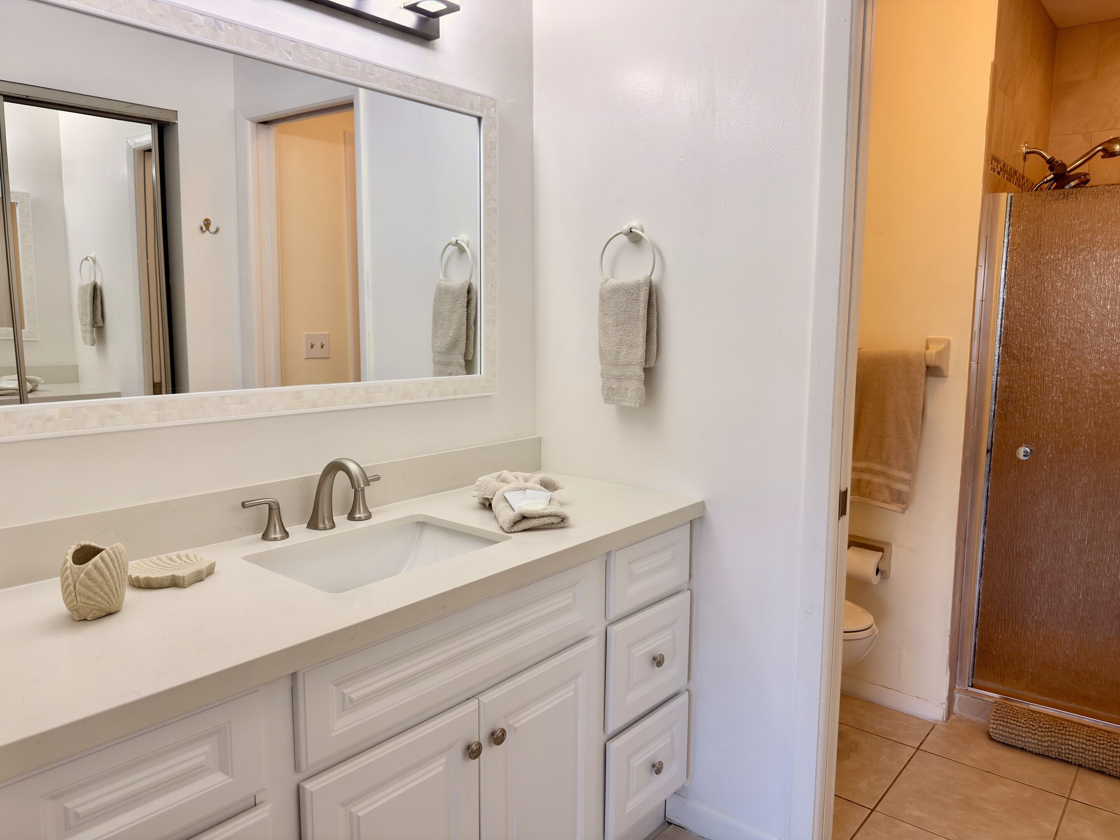 Un bagno con lavandino bianco, specchio e porta asciugamani.
