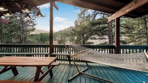 A wooden deck with picnic tables and a hammock.