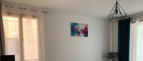 Een moderne woonkamer met een grijze bank, kussens in groentint, een witte tafel en een vloerlamp.
