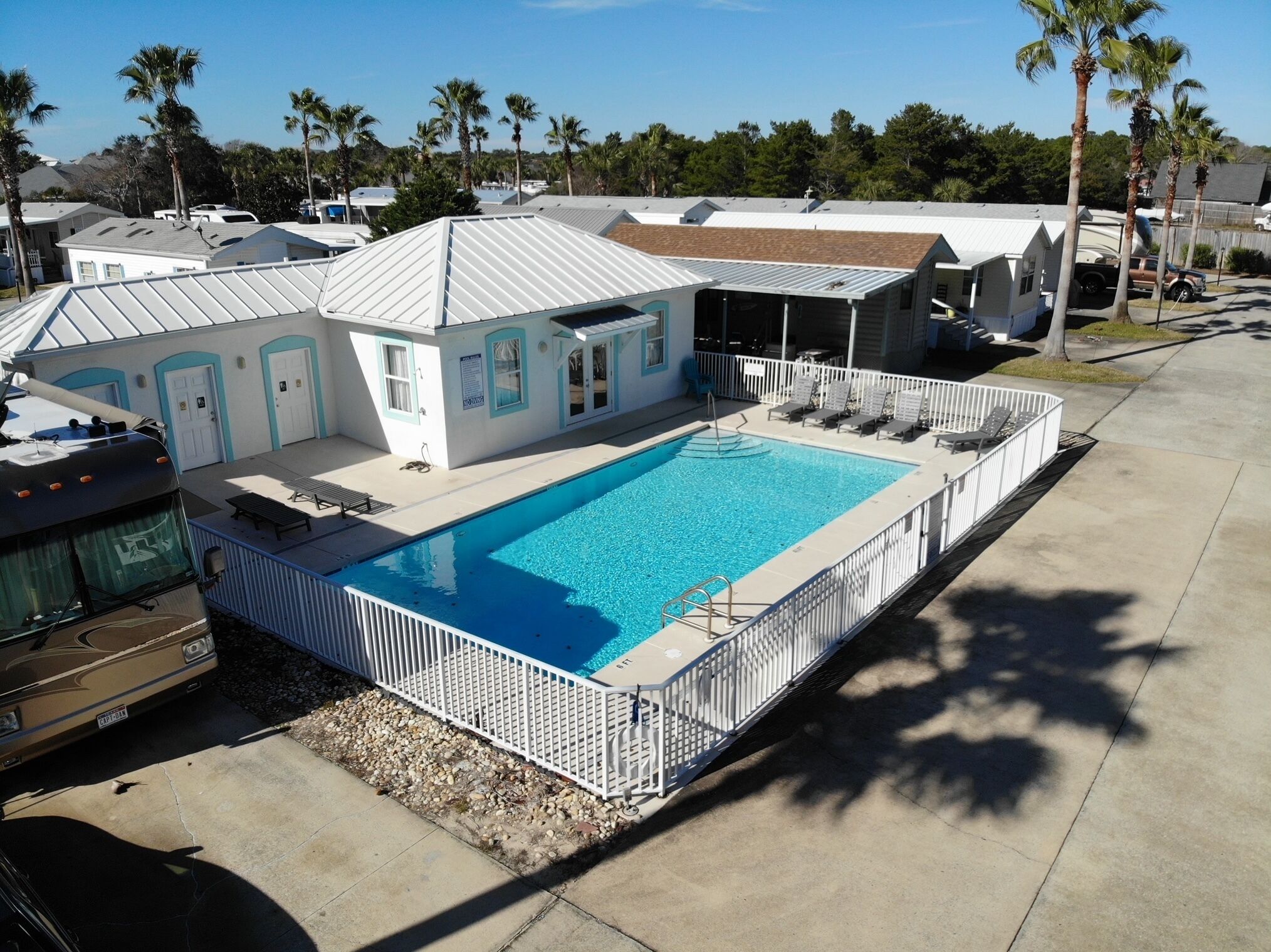 A residential property with a swimming pool, a covered patio, and a vehicle parked nearby.