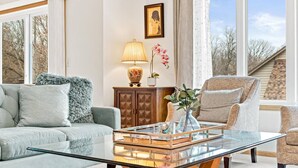 A living room with a glass coffee table, a sofa, a chair, a cabinet, and a framed picture on the wall.