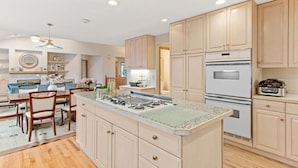 A modern kitchen with a central island, built-in appliances, and a dining area with a blue sofa and table.