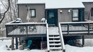 A two-story building with a snow-covered deck and a small staircase leading to the entrance. - Camelback mountain condo with incredible views! Quick walk to the slopes!  (Tannersville)